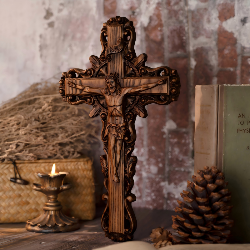 Hand-carved dark wood crucifix with a relief sculpture of Jesus Christ, featured with ornamental scrollwork edges next to a glowing candle on a wooden table