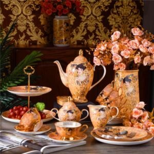 A lavish porcelain tea and dinner set featuring intricate golden motifs and classical portrait illustrations in the style of Gustav Klimt, displayed on a table alongside floral vases, a tiered fruit tray, and scattered dinnerware