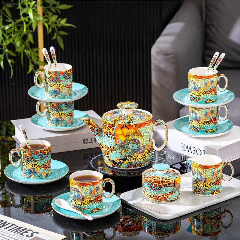 Comprehensive porcelain tea set displayed on a table featuring a teapot, sugar bowl, creamer pitcher, and multiple coffee cups on light blue saucers with gold-accented animal print and artistic patterns