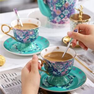 Hands holding a matching ceramic teacup and stirring with a spoon, part of a set featuring teacups with pedestal bases, saucers, and a teapot, all decorated in a vibrant turquoise and purple mosaic tile pattern