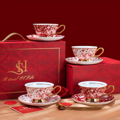 A luxury ceramic teacup and saucer set displayed alongside a red "Ritual of Life" gift box, featuring four teacups and matching saucers adorned with intricate red floral patterns and gold accents, accompanied by gold spoons