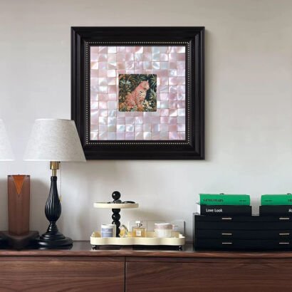 A square framed art piece hanging above a console table, featuring a mosaic background made of shimmering pink mother-of-pearl tiles with a small, detailed painting of a leopard nestled in the center