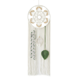 A handmade white macrame wall hanging featuring a circular woven ring accented with wooden beads, hanging fringe, and three distinct leaf-like pendants including a green leaf and a beaded strand