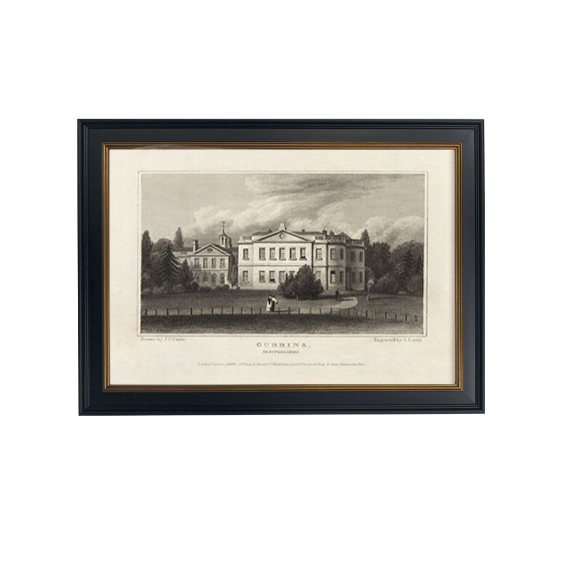 A framed black and white historical etching depicting a grand European estate mansion with grounds and a fence in the foreground, set against a white mat inside a black frame with thin gold inner lining