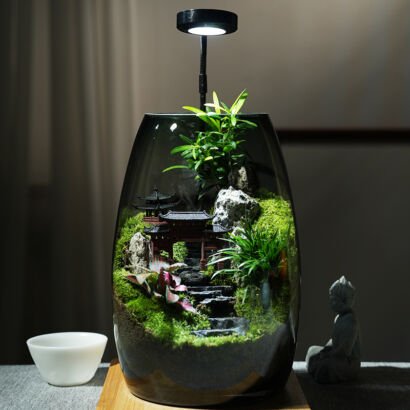 A smoky glass terrarium featuring an intricate Chinese garden landscape with miniature pagodas, natural rock formations, stone steps, lush moss, and small green plants, topped with an overhead LED grow light on a wooden base.