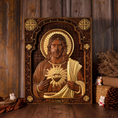 An upright rectangular wooden wall plaque featuring a detailed high-relief carving of the Sacred Heart of Jesus in dark wood with golden halo and robe accents, framed within an intricately carved and patterned architectural border, displayed on a wooden surface with a pinecone and decorative items.