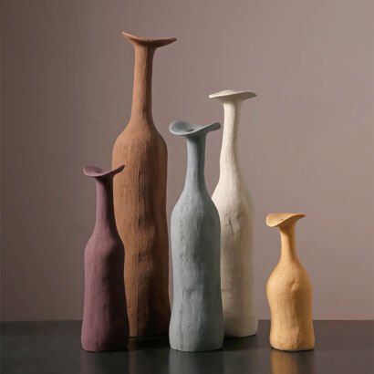 Collection of five long-necked, organic hand-molded clay ceramic vases in clay terracotta, dusty plum, slate blue, off-white, and warm ochre tones
