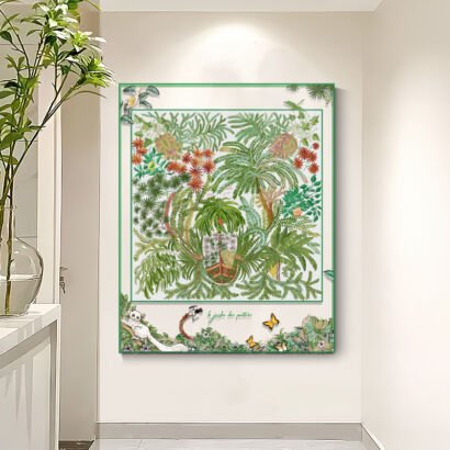 A large transparent acrylic art display frame mounted on a modern entryway wall next to a potted green plant, featuring a central silk scarf illustration of lush tropical palm foliage and exotic flora, with a long-tailed lemur, butterflies, and leafy vines extending onto the outer clear frame border.