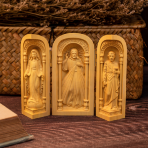 Three-panel carved wooden folding triptych shrine featuring Jesus Christ, the Virgin Mary, and Saint Joseph displayed on a wooden surface