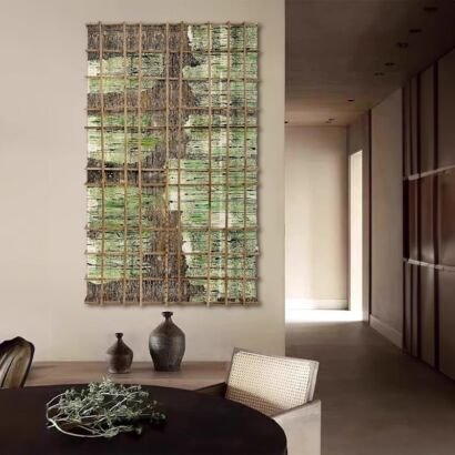 A large vertical textured tapestry wall art with a natural wooden grid frame overlay displaying woven moss green, charcoal grey, and earth-toned bark textures hanging in a modern minimalist interior.