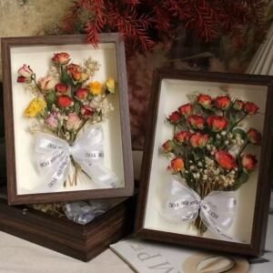 Dried rose flower shadow box frames, preserved tiny rose bouquets with white printed ribbon bows displayed in dark wood deep picture frames