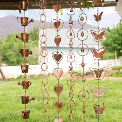 Vintage copper-toned metal hanging ornament strings, assorted garden motif wind chime strands with watering cans, rings, hearts, teardrops and butterflies suspended under wooden beam