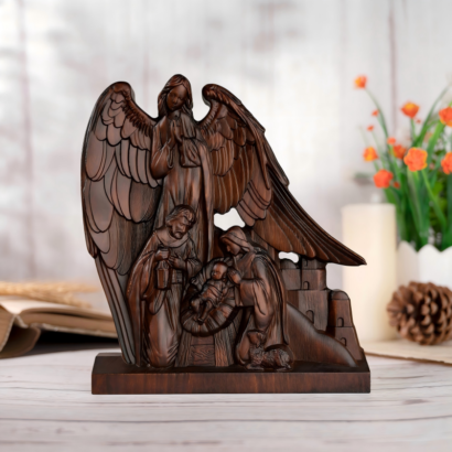 A detailed dark wood carved figurine depicting a traditional Nativity scene with Mary, Joseph, and the Christ Child in a manger, watched over by a large winged guardian angel standing behind them, displayed on a wooden surface.