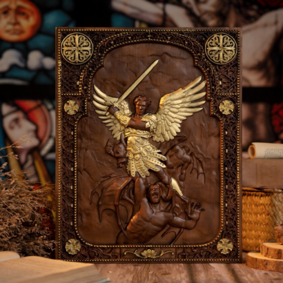 An upright rectangular wooden wall plaque featuring a detailed high-relief carving of Archangel Michael with golden wings and armor triumphantly striking a defeated demon with a sword, enclosed within an intricately carved and accented border, displayed on a wooden surface.