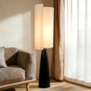 Modern floor lamp with black tapered base and split beige fabric shade placed beside sofa in bright living room