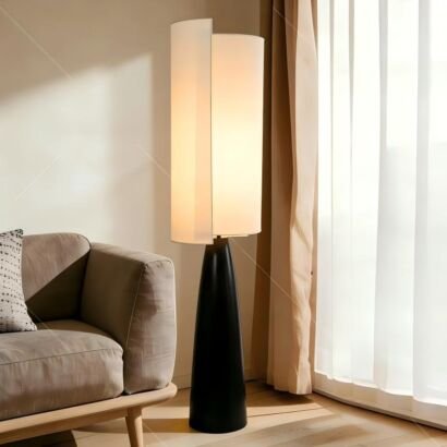 Modern floor lamp with black tapered base and split beige fabric shade placed beside sofa in bright living room