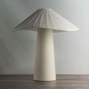 A modern off-white ceramic table lamp featuring a tapered conical base and a wide pleated umbrella-shaped mushroom shade on a wooden surface against a neutral background.