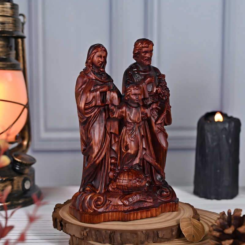 A dark wood carved figurine of the Holy Family standing on a rustic wooden slice base, featuring Mary and Joseph standing behind the young Jesus who stands atop a globe, displayed on a table with a lantern and a lit candle.