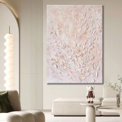 A large vertical 3D textured abstract canvas painting with sculpted white flower petals and subtle gold accents on a soft blush pink background hanging in a modern living room.