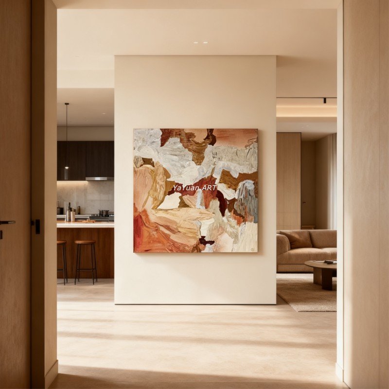 A large square abstract canvas painting featuring textured brushstrokes in terracotta, warm beige, brown, and cream mounted on a neutral wall in a modern open-concept home