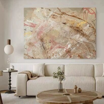 A large abstract canvas painting featuring neutral beige, soft pink, and earthy brown brushstrokes hanging above a modern cream sofa in a bright living room.