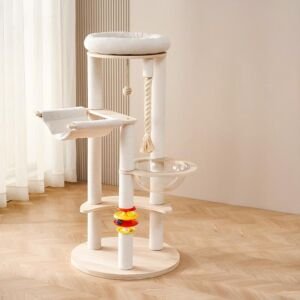 A modern light-wood multi-level cat tree featuring white sisal-wrapped scratching posts, a plush top bed, a clear acrylic space capsule bowl, a soft fabric hammock, a dangling rope with a ball toy, and a colorful multi-level track ball toy near the base, set on a wooden floor in a brightly lit room.