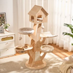 A tall, tree-shaped natural wooden cat tower featuring a house-shaped top condo with a cushion, two plush round perches, a fabric hammock, a clear acrylic bowl hammock with an orange tabby cat lying inside, and hanging plush toys, set in a bright modern living room.