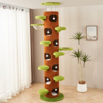 A tall, floor-to-ceiling tree trunk-inspired cat tower featuring textured brown bark fabric, multiple green plush leaf-shaped stepping perches, stacked round cutout condo hideaways with hanging white pom-poms, and transparent acrylic bowl hammocks in a modern living room setting.