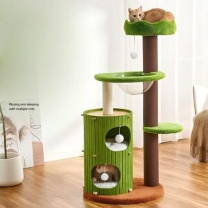 A tall, nature-inspired multi-level cat tree featuring vibrant green plush perches, a tall brown main post, a green cylindrical two-story cat condo, a transparent acrylic bowl hammock, dangling plush pom-poms, and an orange tabby cat resting at the top perch.