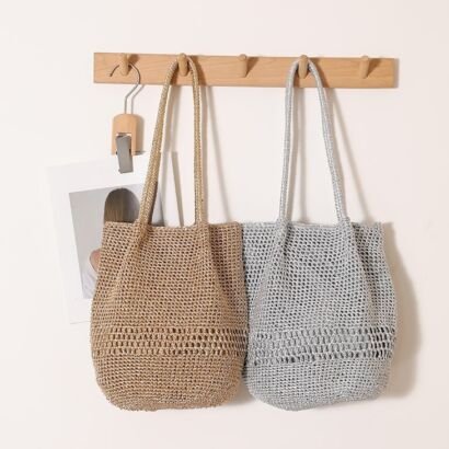 Two glittery crochet woven straw tote bags in metallic gold and metallic silver hanging side-by-side on a wooden wall rack, featuring long matching woven shoulder straps.