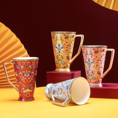 Four tall ceramic coffee mugs with traditional Chinese imperial enamel floral patterns in red, yellow, pink, and light blue with elegant gold handles