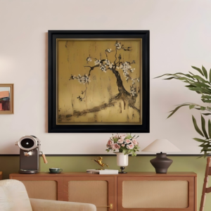 A square framed art piece hanging on a warm neutral wall above a wooden media console, featuring a dark blossoming plum tree branch sprawling across a textured metallic gold leaf background inside a black and gold frame.