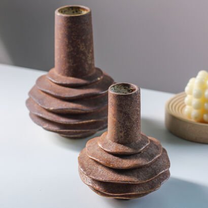 Brown textured ceramic vases with stacked tiered design and cylindrical necks on a tabletop
