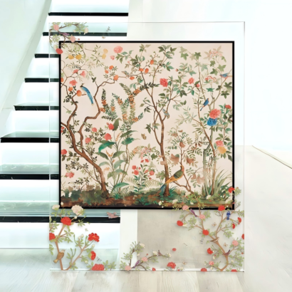 A large transparent acrylic art display placed on the floor near a staircase, featuring a framed silk scarf illustration of a traditional Chinoiserie garden with blooming flowers, delicate branches, and songbirds.