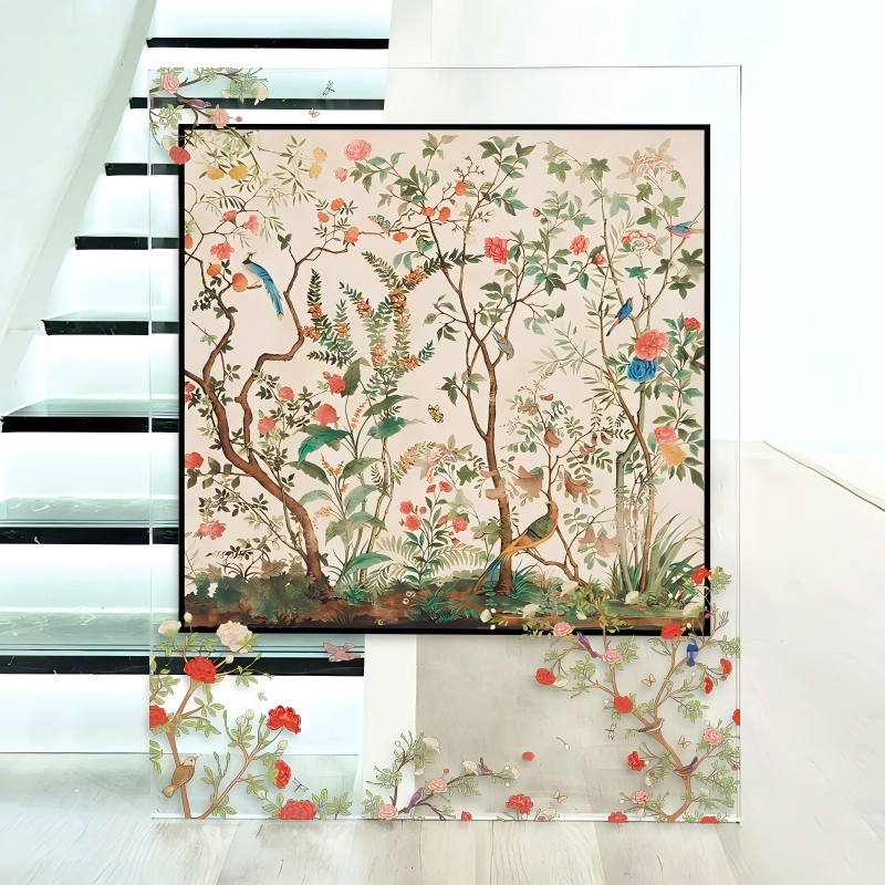 A large transparent acrylic art display placed on the floor near a staircase, featuring a framed silk scarf illustration of a traditional Chinoiserie garden with blooming flowers, delicate branches, and songbirds.