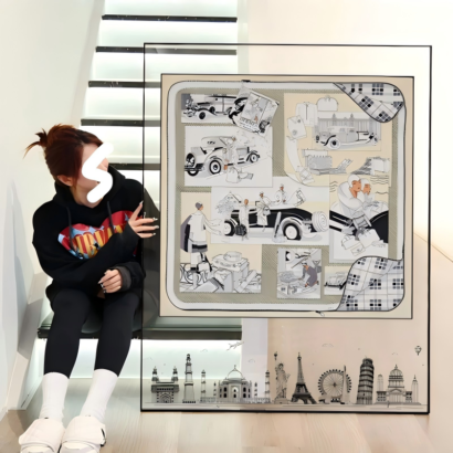 A large square acrylic floating frame displaying a framed silk scarf with vintage motoring and travel sketch illustrations, featuring a black skyline print along the bottom edge.