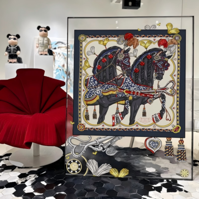 A large acrylic framed wall art featuring a detailed equestrian illustration of two black horses with ornate red and gold reins, displayed next to a red designer accent chair.