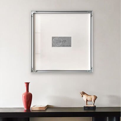 A square silver-framed minimalist art piece featuring Newton's Law of Universal Gravitation formula centered on a white canvas background above a dark console table.