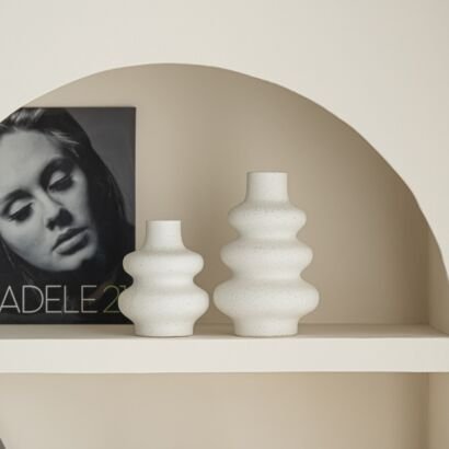 Two off-white speckled ceramic bubble vases with tiered stacked design displayed on an arched wall shelf