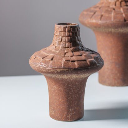 Earthy brown terracotta ceramic vase with textured grid pattern neck and wide pedestal base on display