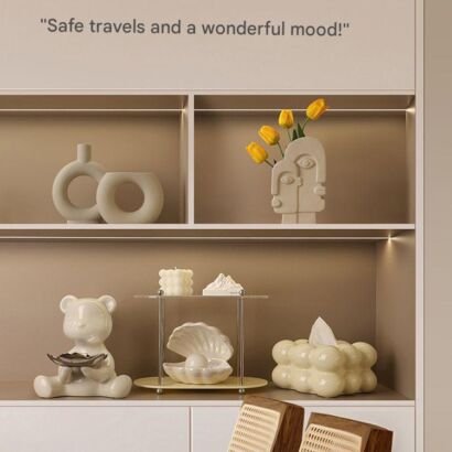 Minimalist cream ceramic face-shaped vase holding yellow tulips displayed on a modern backlit wall shelf alongside hollow donut vases and decorative home accents