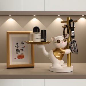 Cute white cat figurine wearing gold sunglasses and a vest holding a small gold tray with perfume and leaning against a key rack pole holding car keys and a watch