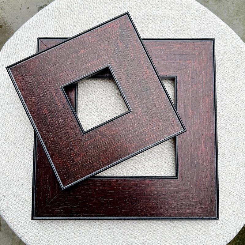 Square flat dark reddish-brown wood grain picture frames, two layered hollow wooden frame blanks with thin black inner trim on white linen surface
