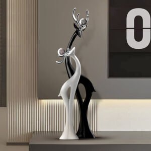 Sleek black and white abstract deer figurines with stylized chrome antlers and silver spheres standing on a dark table in a modern living space