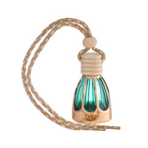 A small hanging car perfume diffuser bottle made of translucent emerald green ribbed glass encased in a metallic gold base, topped with a natural wooden cap and adjustable braided beige cord with gold thread accents.