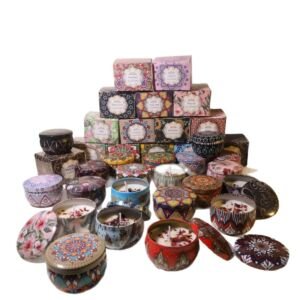 A variety pack of small scented soy candles in colorful bohemian mandala printed tin containers, arranged with open lids showing dried floral toppings alongside stacked matching gift boxes.