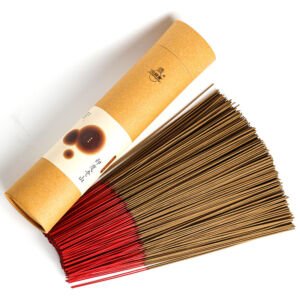 A fan of natural sandalwood incense sticks with red-dipped bamboo ends laid out beside an eco-friendly round kraft paper packaging tube.