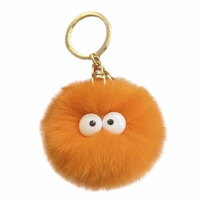 A vibrant orange fuzzy faux-fur pom pom keychain featuring large white googly-style eyes and a sturdy gold metal keyring on a plain white background