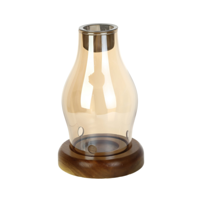 An isolated studio product shot of a glass essential oil burner and candle holder with a warm amber-tinted glass shade, a dark wooden base, ventilation holes near the bottom, and a metal oil tray top insert against a white background.