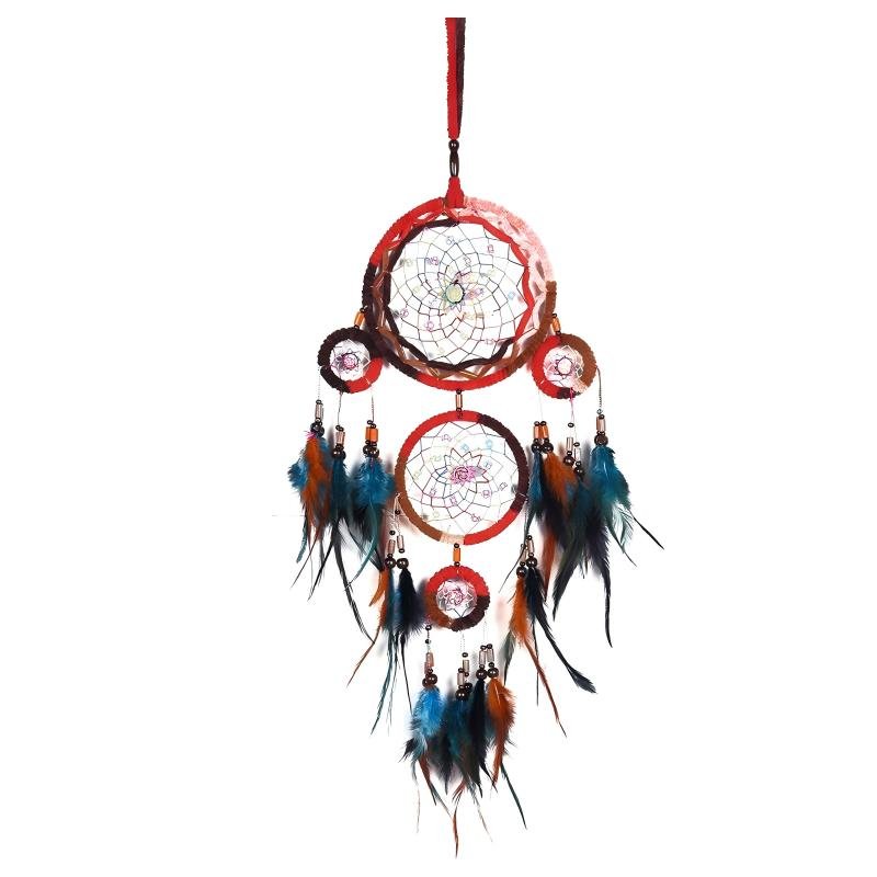 A detailed handmade dream catcher featuring multiple hoops with a vibrant red frame and cascading blue and brown feathers, hanging against a white wall.